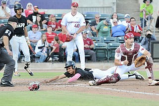 UAPB designated hitter Carlos Rodriguez-Velez slides home to score a run behind Arkansas catcher Ryder Helfrick at Dickey-Stephens Park in North Little Rock on Tuesday. (Special to the Commercial/William Harvey)